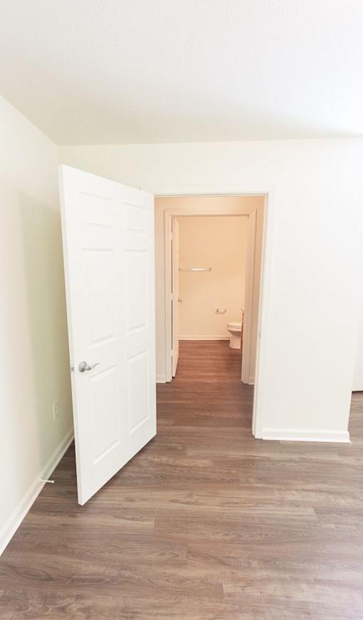 A hallway with a white door and a wooden floor.