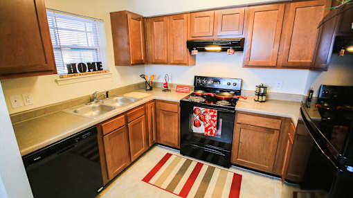 A kitchen with a black stove top oven and wooden cabinets.