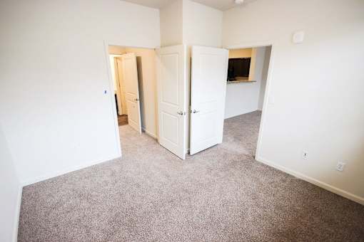 A carpeted room with a white door and a white wall.