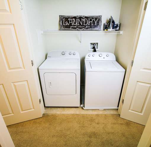 A laundry sign is above a washer and dryer in a small room.