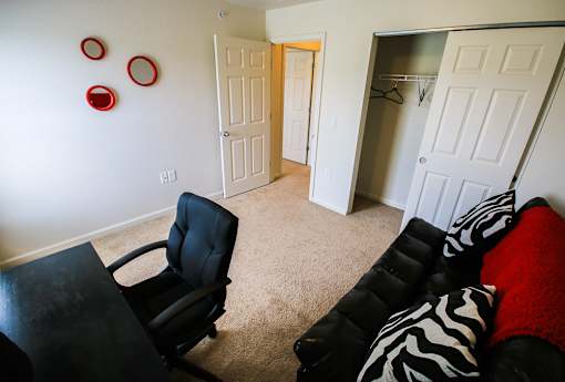 A black chair is in a room with a zebra print couch.