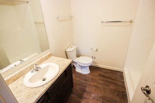 A white toilet sits in a bathroom next to a sink.