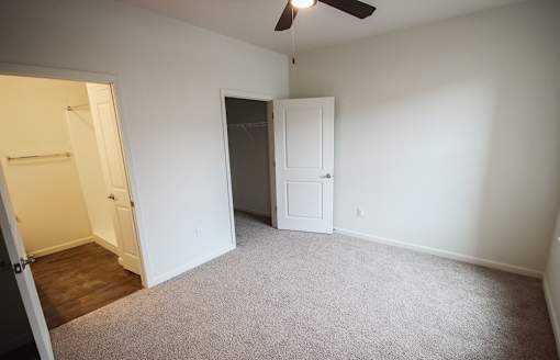 A room with a ceiling fan and two doors.