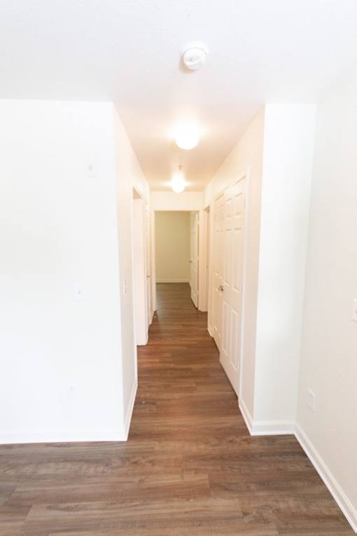 A long hallway with wood floors and white walls.