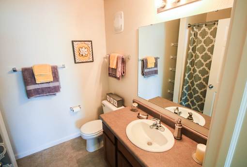 A bathroom with a toilet, sink, mirror, and towel rack.
