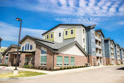 A large apartment complex with multiple buildings and a parking lot in front.
