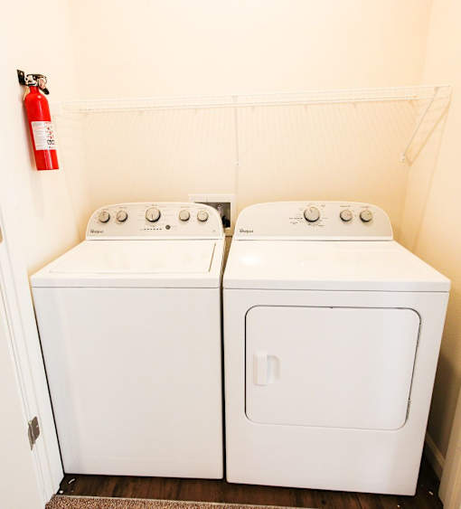 Two white front loading washing machines in a small laundry room.