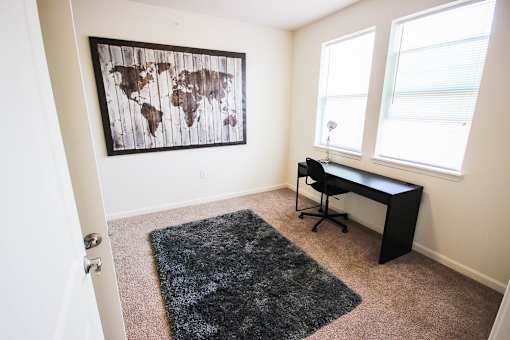 A room with a world map on the wall and a black desk with a chair.