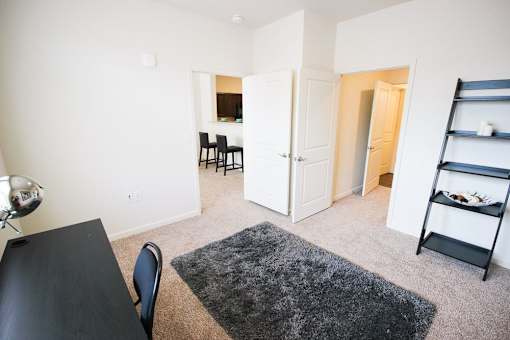 A black table and chairs are in a room with a rug on the floor.