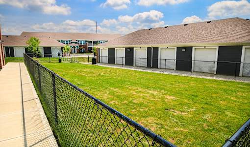 A dog park with a black fence with apartment buildings in the background