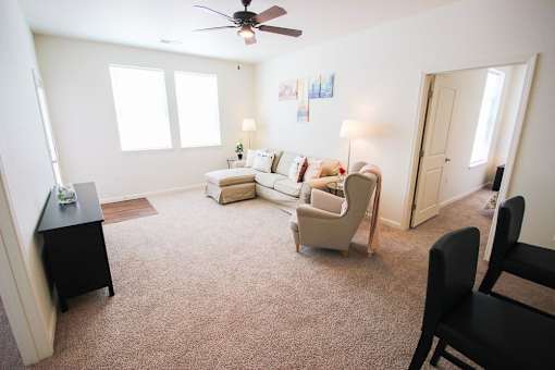 A living room with a couch, chair, and a fan.