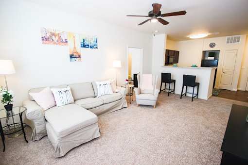 A living room with a white couch and a fan.