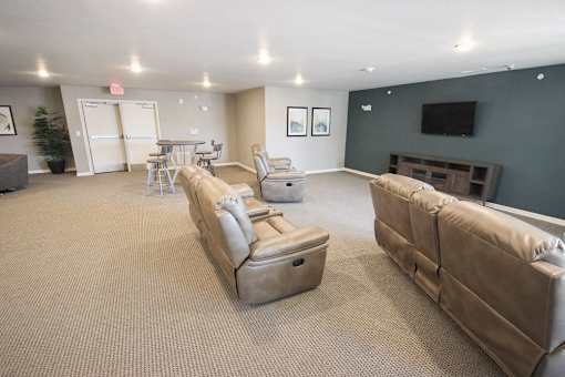 A living room with a couch, chairs, and a television.