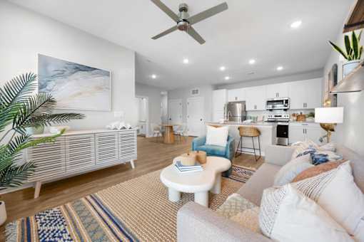 A living room with a white couch and a painting on the wall.