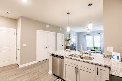 an open kitchen and living room with white cabinets and a counter top