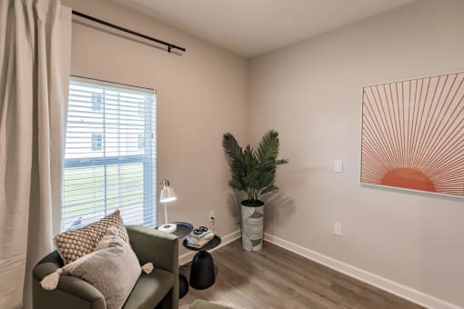 small room with a chair, end table and a plant at  a living room with tables and chairs and a ceiling fan at Swiftwater apartments in Port Charlotte, FL