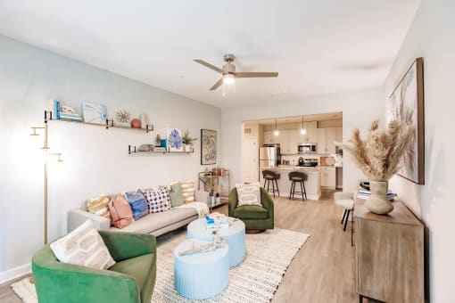 a living room with furniture and a ceiling fan and a kitchen in the background at  a living room with tables and chairs and a ceiling fan at Swiftwater luxury apartments in Port Charlotte, FL