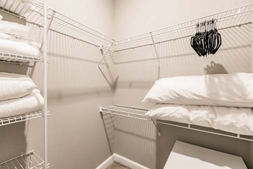 a walk in closet with a bed in it and a rack with white pillows