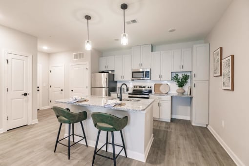 an open kitchen with a large island with two stools at swiftwater luxury apartments in port charlotte, fl