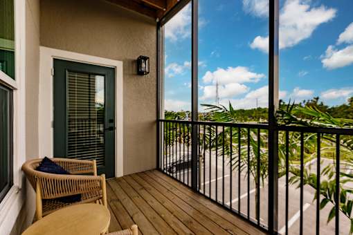 a screened in balcony with a view of the ocean and a chair and a table