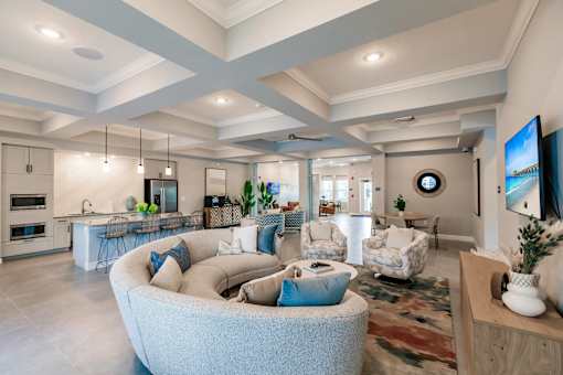 lounge area with a large couch, chairs, and a kitchen in the background at Vantage Luxury Apartments in  Cape Coral, FL
