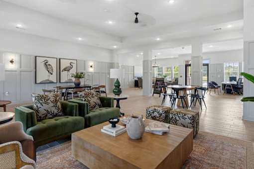 A living room with a green sofa, wooden coffee table, and a painting of a bird on the wall.