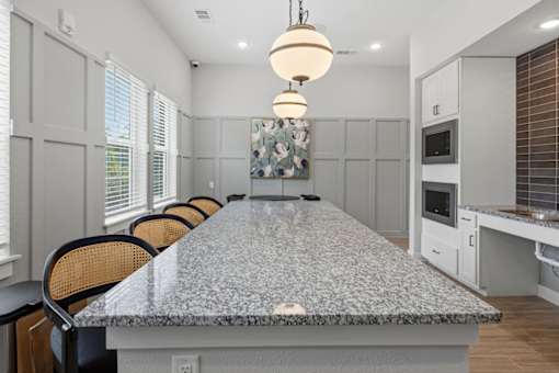 A kitchen with a granite countertop and chairs.