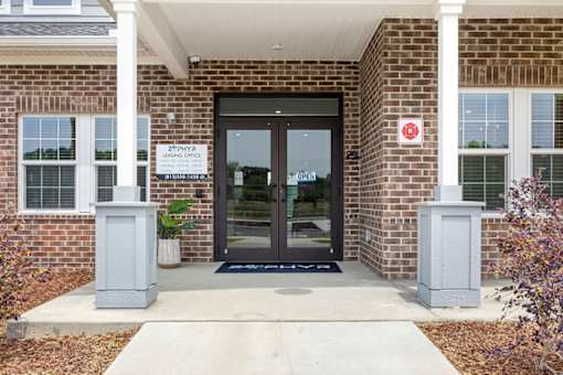 The front of a brick building with a glass door and a sign that says "ZIP+4" on it.