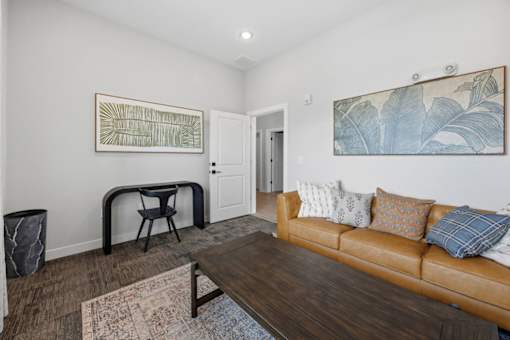 A living room with a brown couch and a painting on the wall.