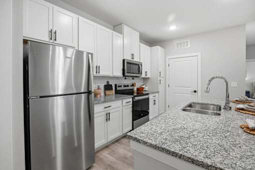 A kitchen with a stainless steel refrigerator, microwave, oven, and sink.