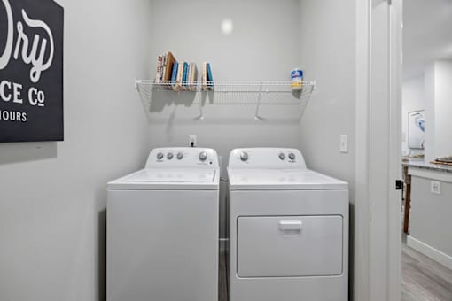 A laundry room with two washing machines and a shelf with laundry products.