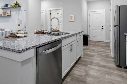 A kitchen with a granite countertop and stainless steel appliances.