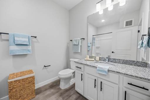 A bathroom with a toilet, sink, and mirror.