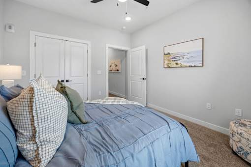A bedroom with a bed in the center and a painting on the wall.