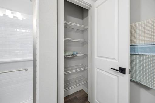 A white pantry with an open door revealing empty shelves.