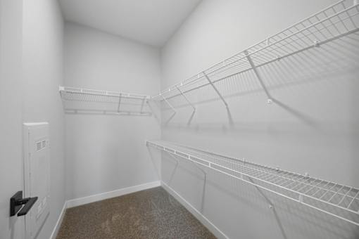A white walk in closet with shelves and a door.