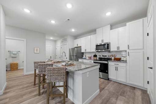 A kitchen with white cabinets and a grey island.