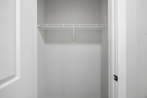 A white empty closet with a door on the right.