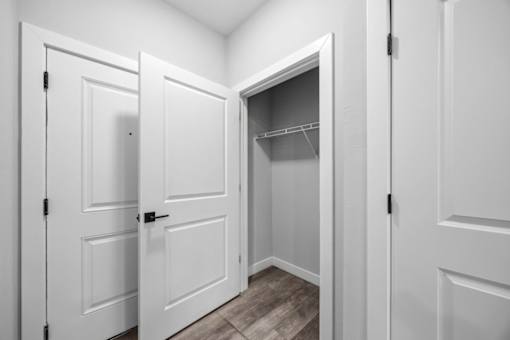 A white closet with a shelf and a door open.