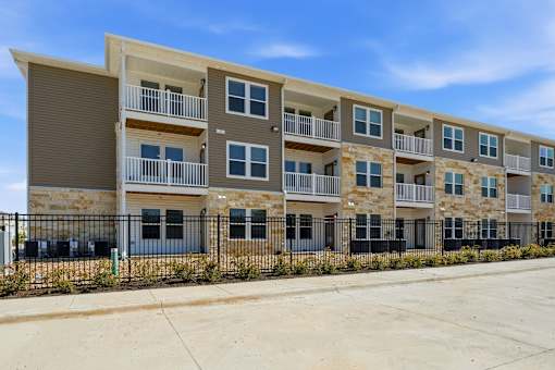 Apartment building with balconies and black fencing.