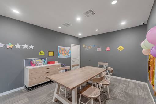 A room with a table, chairs, and a dresser.