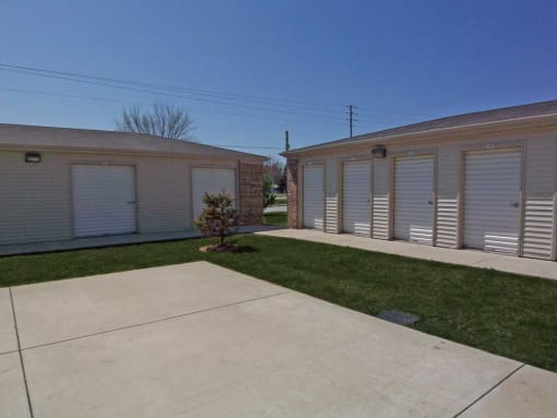 Row of garages with white doors and shutters at Maple Tree Apartments in LaPorte, Indiana