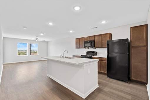A kitchen with a black fridge and wooden cabinets.