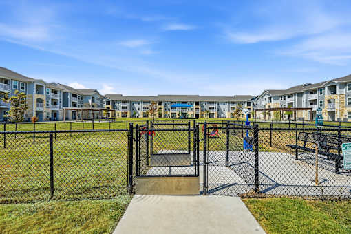 A playground with a slide and a fence in front of apartment buildings.