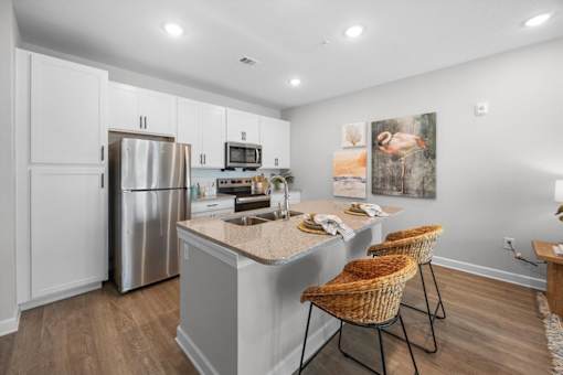 A kitchen with a refrigerator, microwave, and sink.