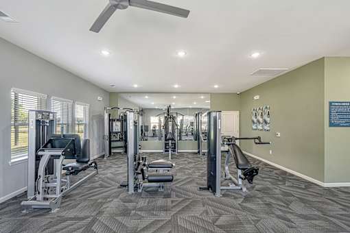 A spacious gym with a variety of equipment and a ceiling fan.