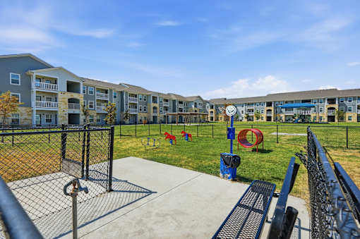 a fenced in dog park with agility equipment