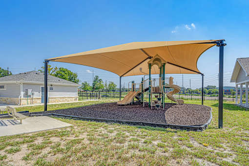 A playground with a yellow canopy and a slide.