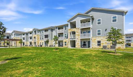 A large grassy area in front of apartment buildings.
