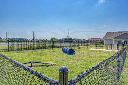 A playground with a blue slide and a fence.